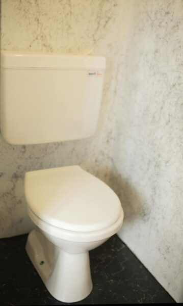 A minimalist white toilet against a marble wall in a sleek bathroom setting.