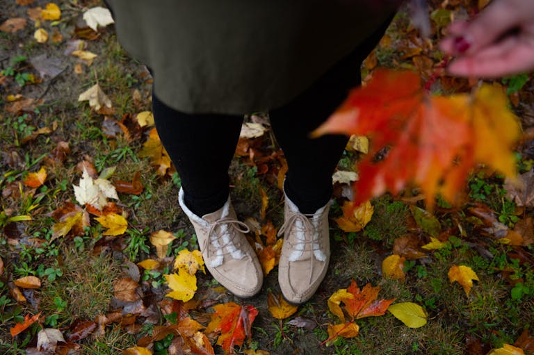 Close-up of a woman's feet on an autumn leaf-covered ground in Orchard Park, NY.