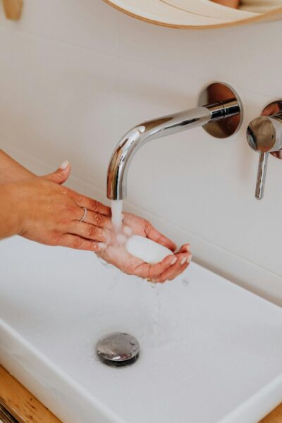 Close-up view of hands washing with soap under running water in a modern bathroom sink.